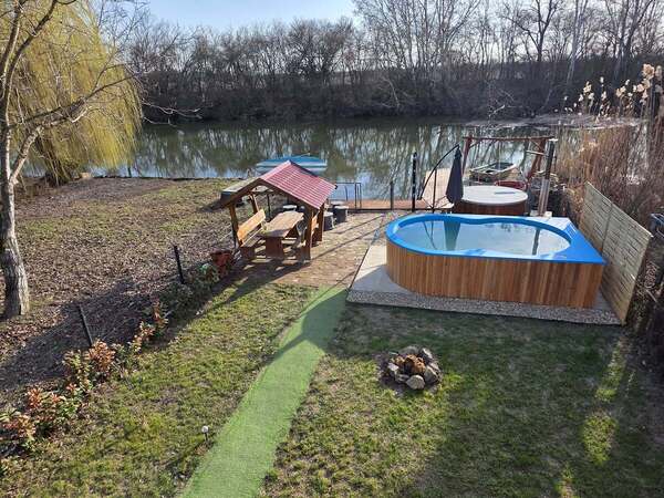 Szembeszomszéd nélküli vízparti nyaraló medencével, csónakkal.